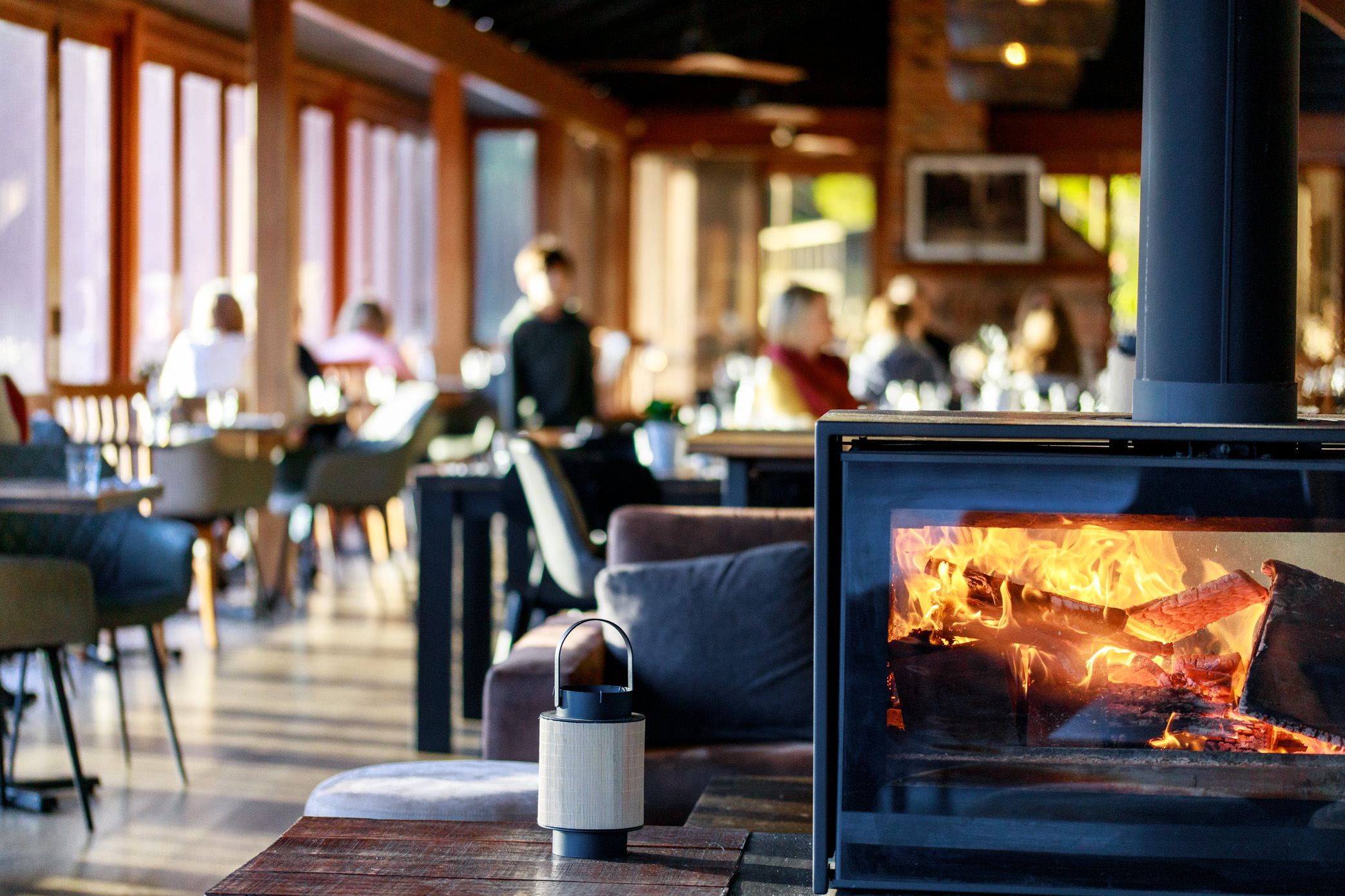 A fireplace glows in the centre of Lakeside Restaurant while diners enjoy a cosy lunch.