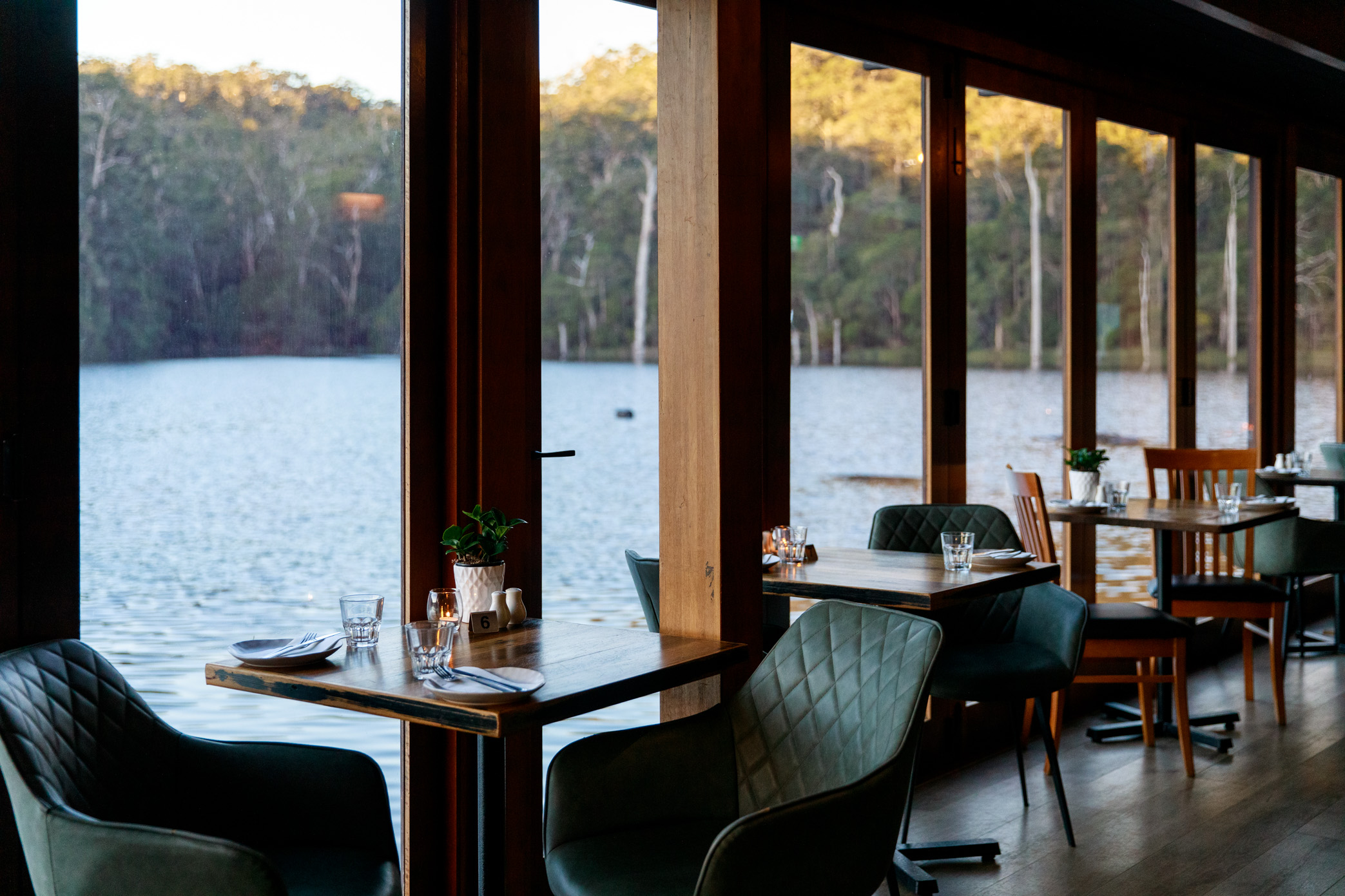 Interior Lakeside Restaurant, empty chairs and table overlooking Lake Beedlup in daytime.