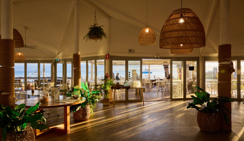 Internals of a restaurant with ocean views out the windows.