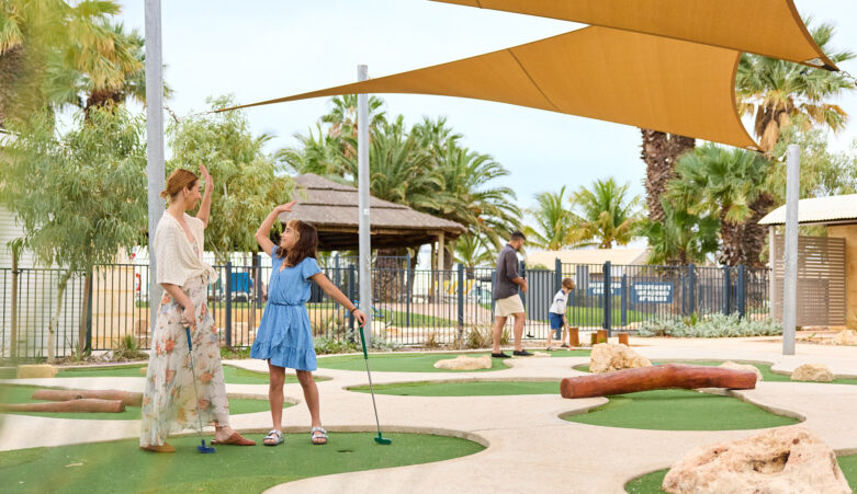 Parent and child high five during a mini golf game