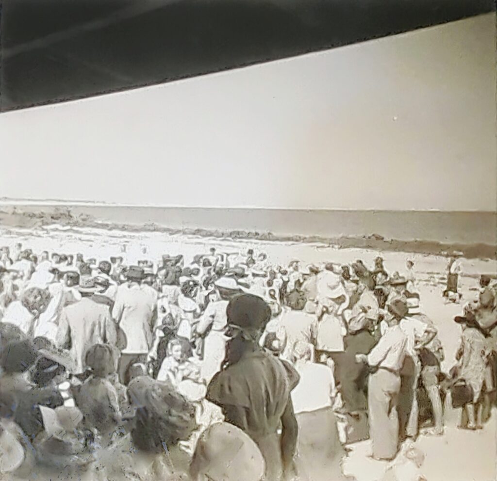 Black and white image of large crowd spilling out of Fresh Air building onto beach.