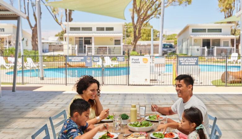 Family of four enjoying lunch poolside at RAC Cervantes Holiday Park