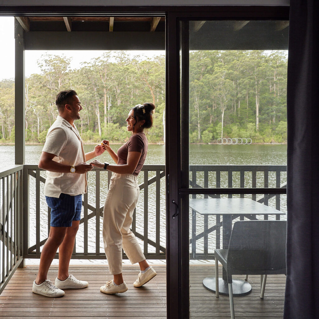 Couple dance on the balcony of a Lakeside Room at RAC Karri Valley Resort