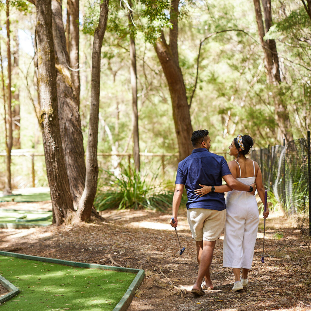 Couple are arms linked on the mini golf course at RA Karri Valley Resort