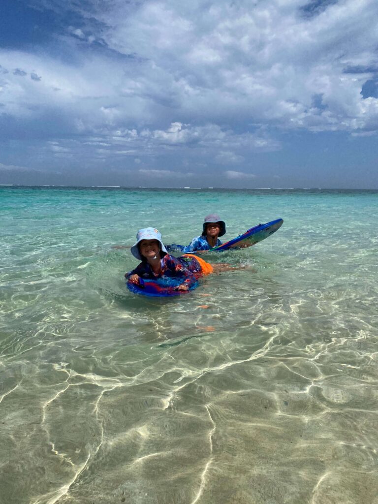 Two children swimming in shallow clear waters