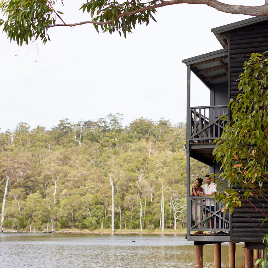 A couple overlook the lake from their balcony at RAC Karri Valley Resort