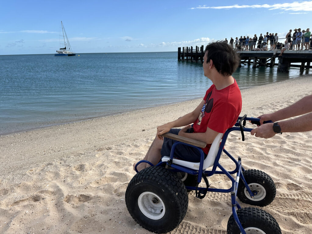 Braeden enjoys dolphin spotting from the waters edge, with the use of the beach wheelchair available for use at RAC Monkey Mia Dolphin Resort.
