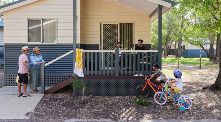 A multi-generational family relax outside a cabin at RAC Busselton Holiday Park