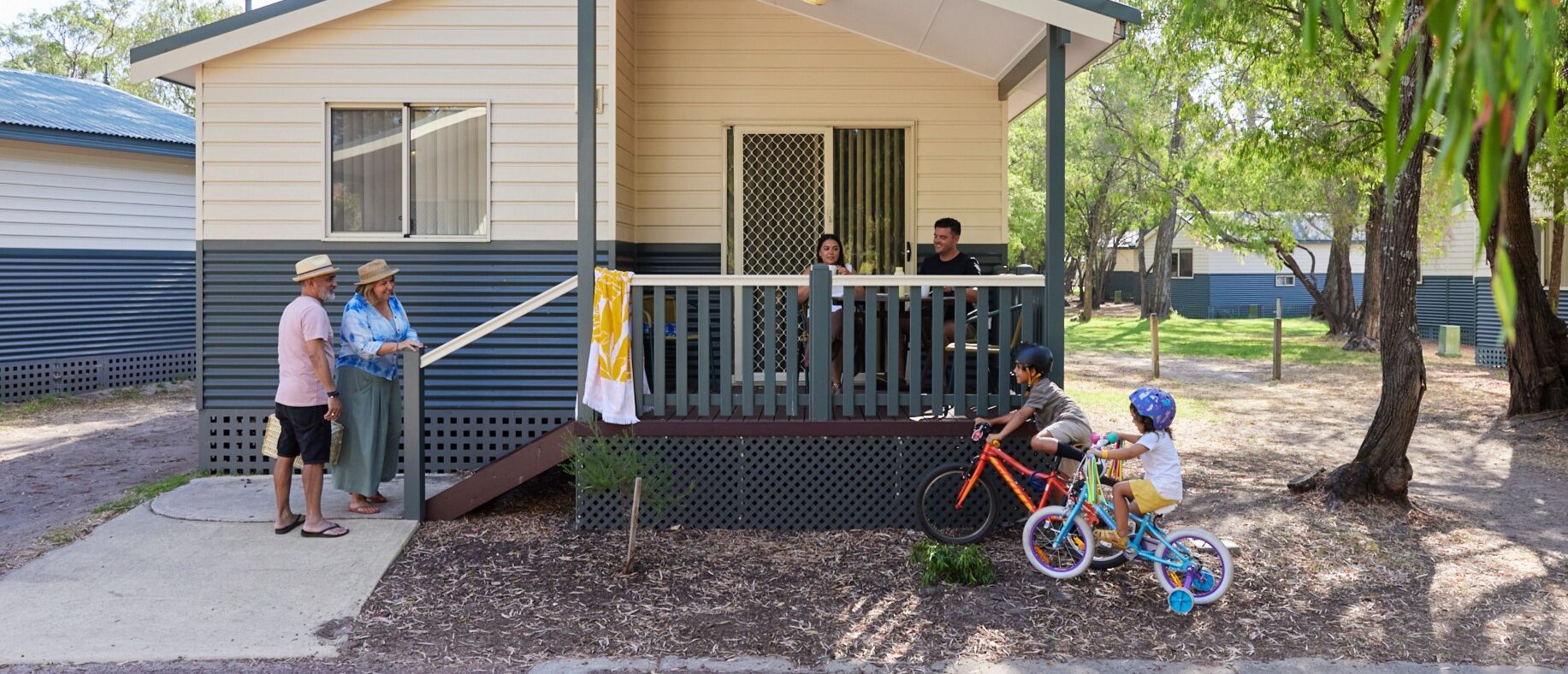 A multi-generational family relax outside a cabin at RAC Busselton Holiday Park