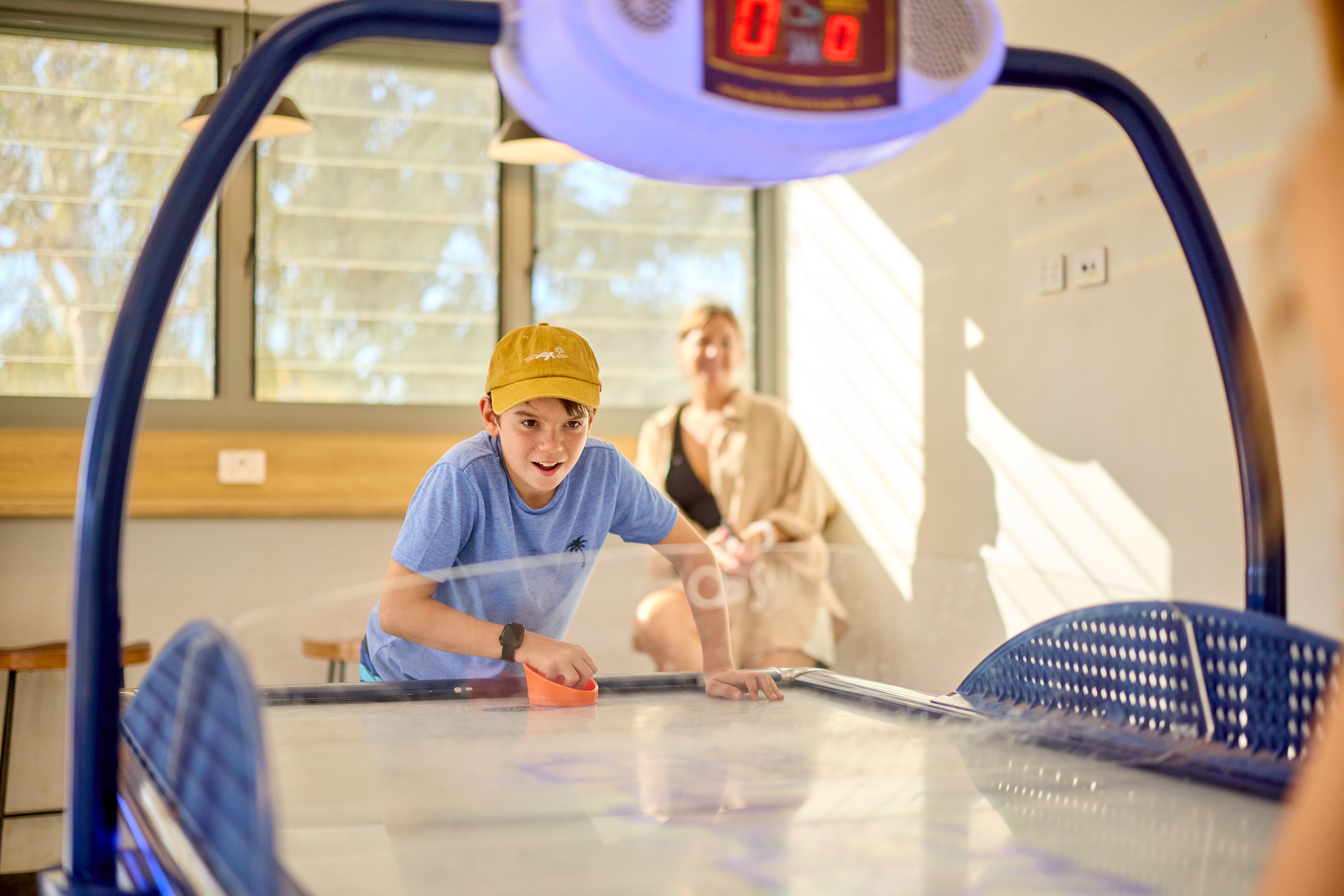 Young guest playing air hockey in the Exmouth recreation room.