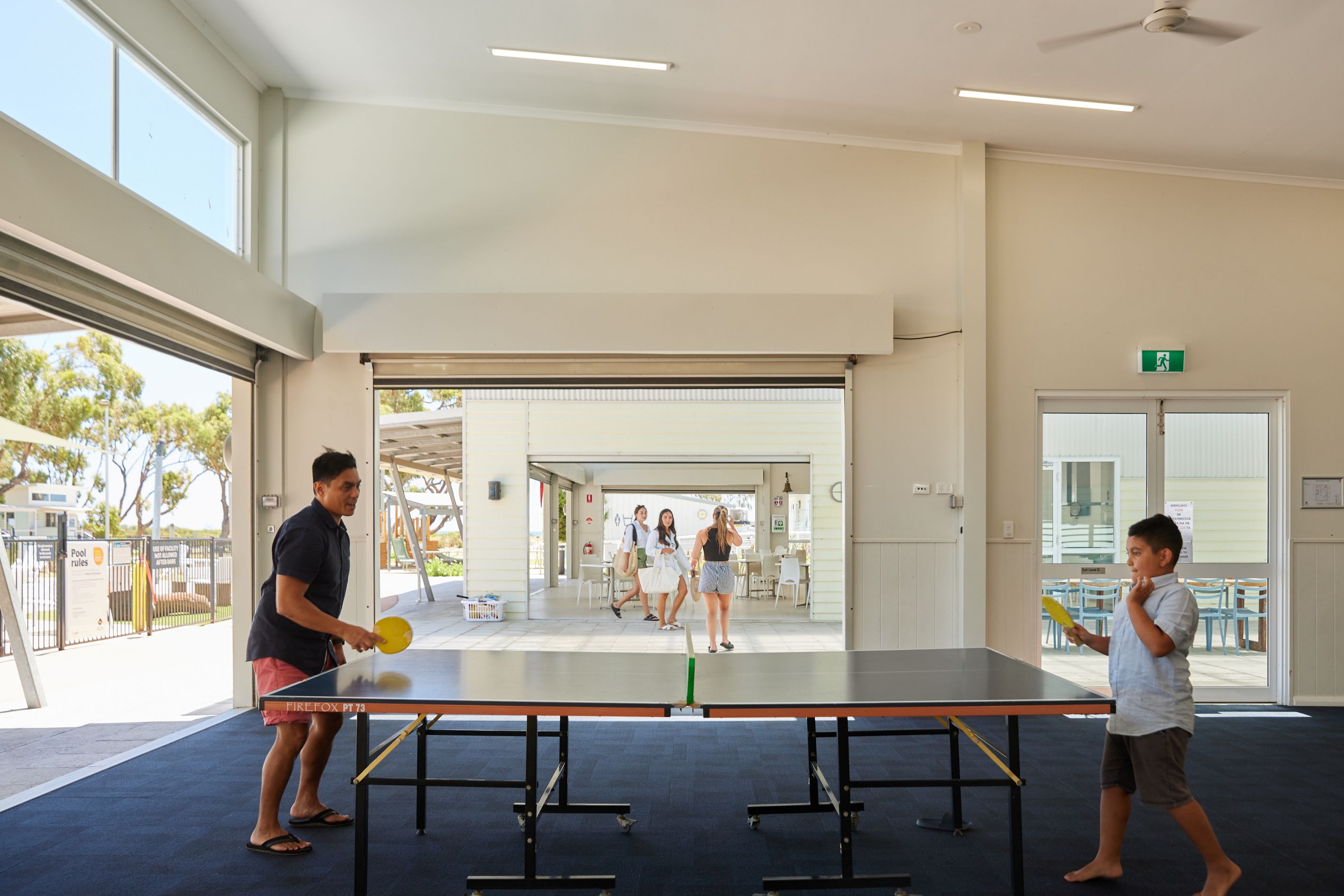 Parent and son playing table tennis in the Cervantes recreation room.