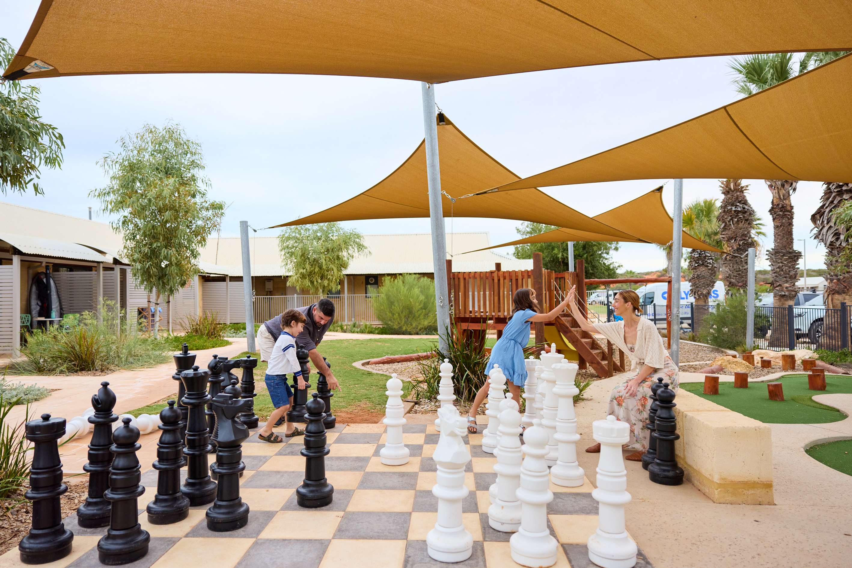 Family playing a game on the giant chess board.