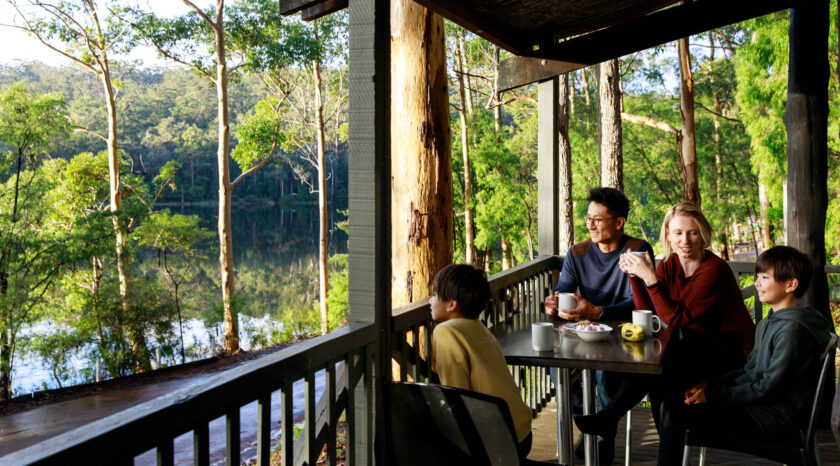 Family enjoying a hot drink on the balcony of a RAC Karri Valley Resort chalet.